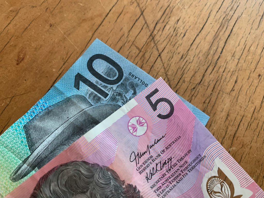 pexels-photo-7654006-7654006 Close-up of Australian 5 and 10 dollar notes on a wooden background.